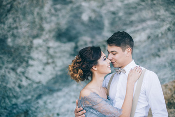 Beautiful couple near the rocks, looking with a smile at each other, hugging wedding day, the bride and groom