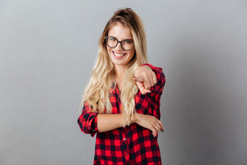 Smiling young blonde woman pointing to you