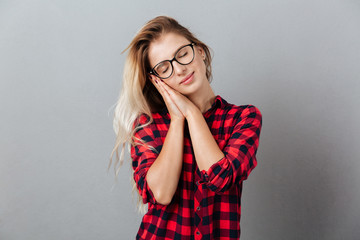 Beautiful young blonde woman showing sleep gesture