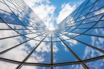Blue sky and white clouds reflecting in a curved glass building