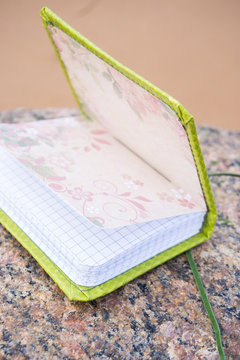 Little green handmade notebook in scrapbooking style with dark green tape and decoration, captured on the stone
