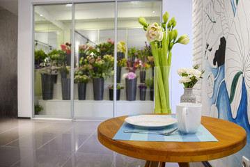 Brown table served with white dishes and two bouquets of flowers