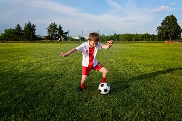 Boy playing with football ball on playing field.