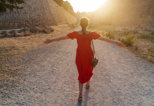 girl goes to meet a bright sun near the ramparts of the island of Rhodes in Greece