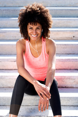 Fototapeta premium Beautiful sporty woman smiling with headphones and sitting on steps