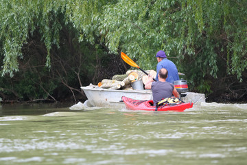 Man in red kayak kayaking in Danube river paddle near a motor boat in Vilkovo