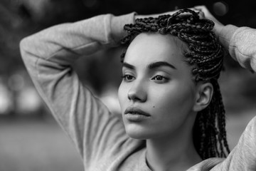 A black-and-white portrait of a beautiful girl with plaited braids.