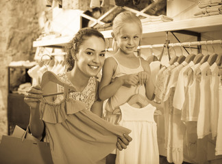 portrait of  woman and girl shopping white baby apparel in clothes store