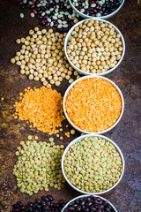 Various lagumes - black, white, red beans, red, green lentils, and chickpeas on old rusty background. Top view, close up.