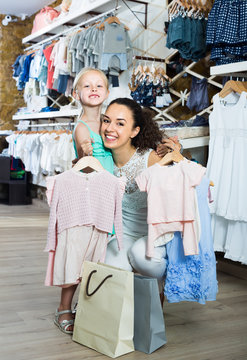 young smiling mother with joyous daughter in shop