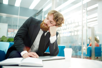 Tired businessman taking nap by his workplace in office during break
