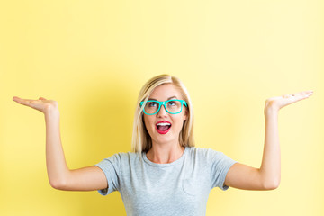 Young woman reaching and looking upwards on a yellow background