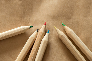 6 colored crayons in random order on beige paper background - text space on top