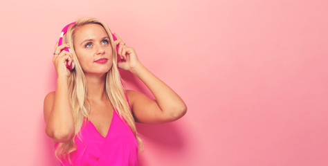  Happy young woman with headphones on a pink background