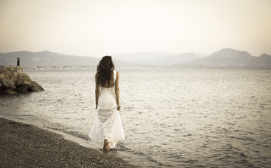 Fototapeta na wymiar Girl standing on the beach with white dress retro photo