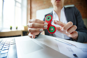 Businesswoman playing with fidget spinner at workplace at break