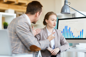 Two young traders discussing new financial project or chart of development