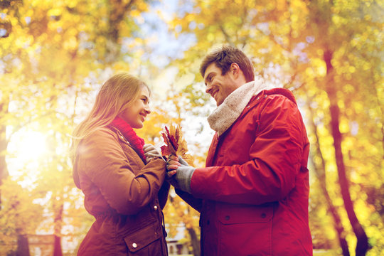 happy couple with maple leaves in autumn park