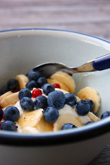 A close-up of a breakfast bowl of fresh fruits and Greek yogurt on a rustic wooden table