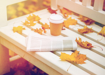 Naklejka na ściany i meble newspaper and coffee cup on bench in autumn park