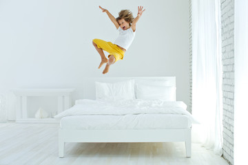 Fototapeta The child is jumping on the bed  obraz