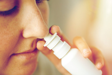 close up of sick woman using nasal spray