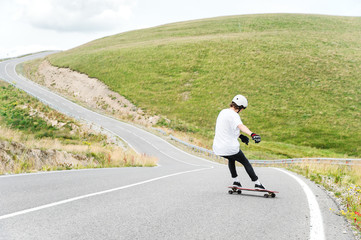 Fototapeta premium A young guy action makes a slide on a longboard in the resort area of the city