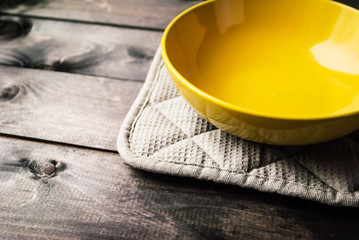 Empty yellow bowl lies on a gray potholder