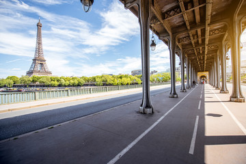 Cityscape view on the old iron bridge with Eiffel tower on the background during the sunny day in Paris