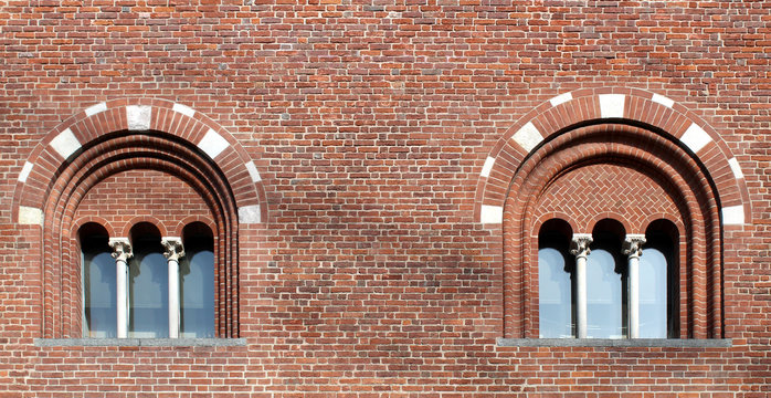 Two mullioned windows with three lights on a brick wall