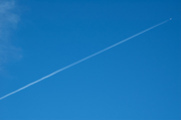 diagonal vapor trail against deep blue sky