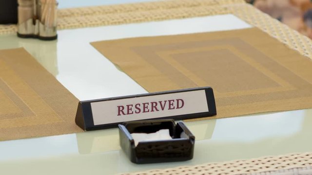 The tablet with the inscription is reserved on the table in an outdoor restaurant video clip with a zoom effect