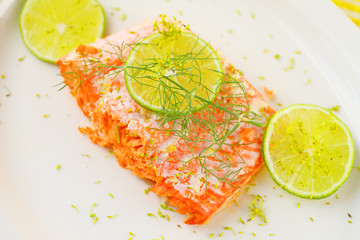 Portion of roasted salmon with lime slices and fresh dill on a white platter with room for text