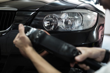 Obraz na płótnie Canvas Car detailing - Hands with orbital polisher in auto repair shop. Selective focus.