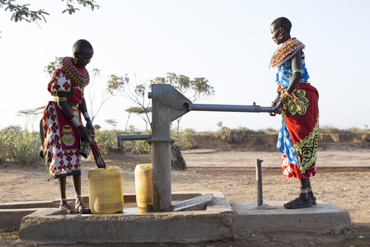 Samburu tribal women collecting fresh water from well in desert landscape. Kenya, Africa.