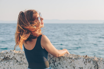 Young woman listening to the music on headphones by the sea