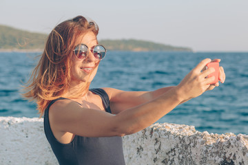 Young woman taking a photo using smartphone by the seaside