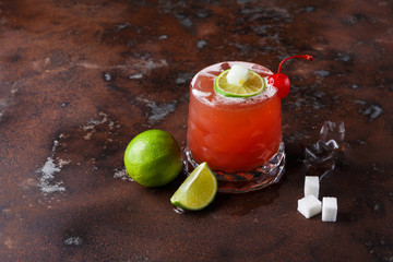 Red cocktail with lime on brown table background