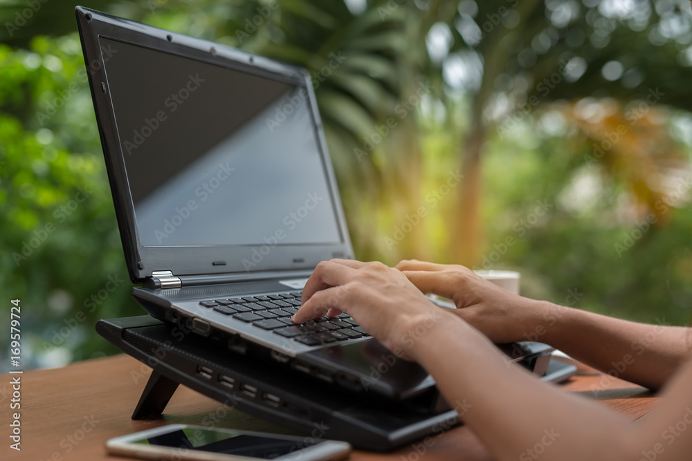 Poster woman's hands on keyboarding while working messaging via social networks using computer laptop. back