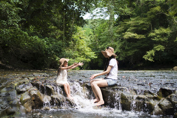 Mother and daughter playing on mountain stream