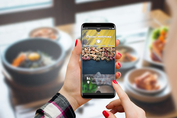 Girl ordering food online on her smartphone, restaurant in background