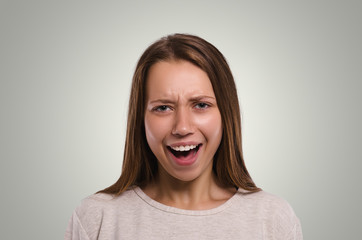 Beautiful  female looking at camera. The girl screams.  Attractive young girl portrait.  Healthy woman studio portrait.