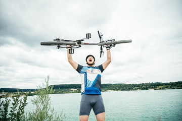 Obraz premium człowiek stoi z rowerem w ręce na wzgórzu i patrząc na jezioro