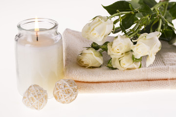 Obraz na płótnie Canvas Spa. Burning candle, white roses and a towel on a white background