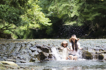 Mother and daughter playing on mountain stream