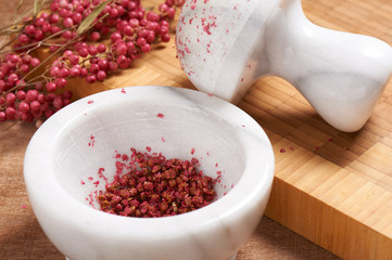 Dry rose pepper in white marble mortar next pestle