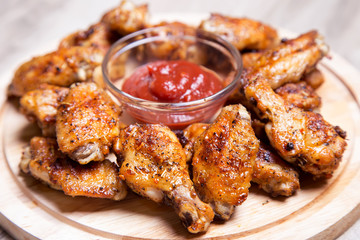 Chicken wings of a barbecue with two sauces on a wooden board. Close-up. Selective focus.