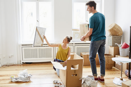 Couple Unpacking Cardboard Boxes At New Apartment