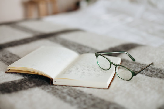 Glasses and journal on a bed