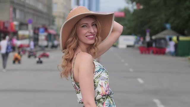 beautiful young blonde woman in a hat walking around the city.slow motion